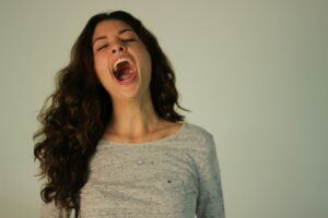 Person sitting calmly indoors, practicing slow breathing with one hand on the chest and another on the abdomen.