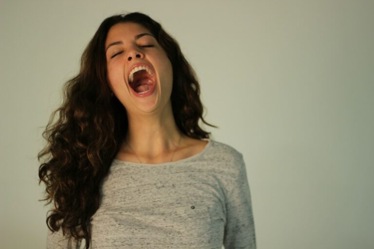Person sitting calmly indoors, practicing slow breathing with one hand on the chest and another on the abdomen.
